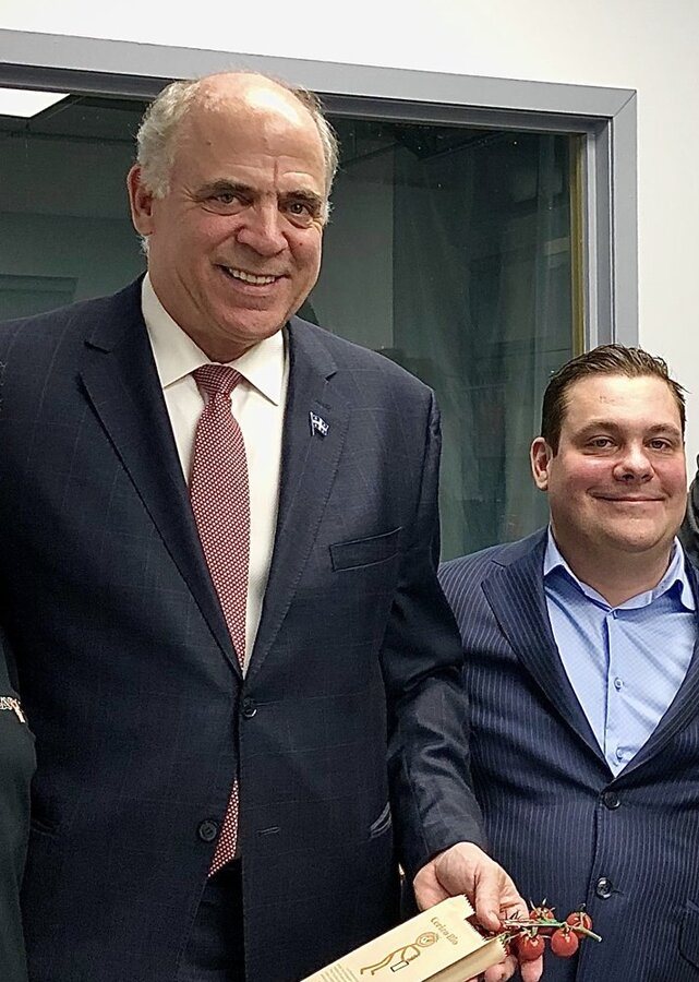 Deux hommes souriants en veston posent dans un couloir.