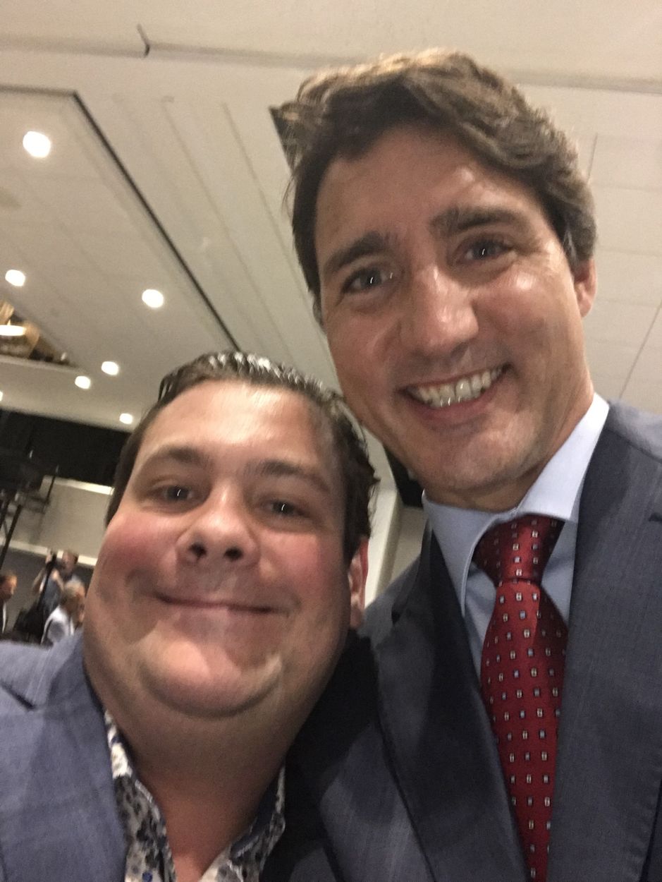 Deux hommes souriants prennent un égoportrait lors d’un événement.