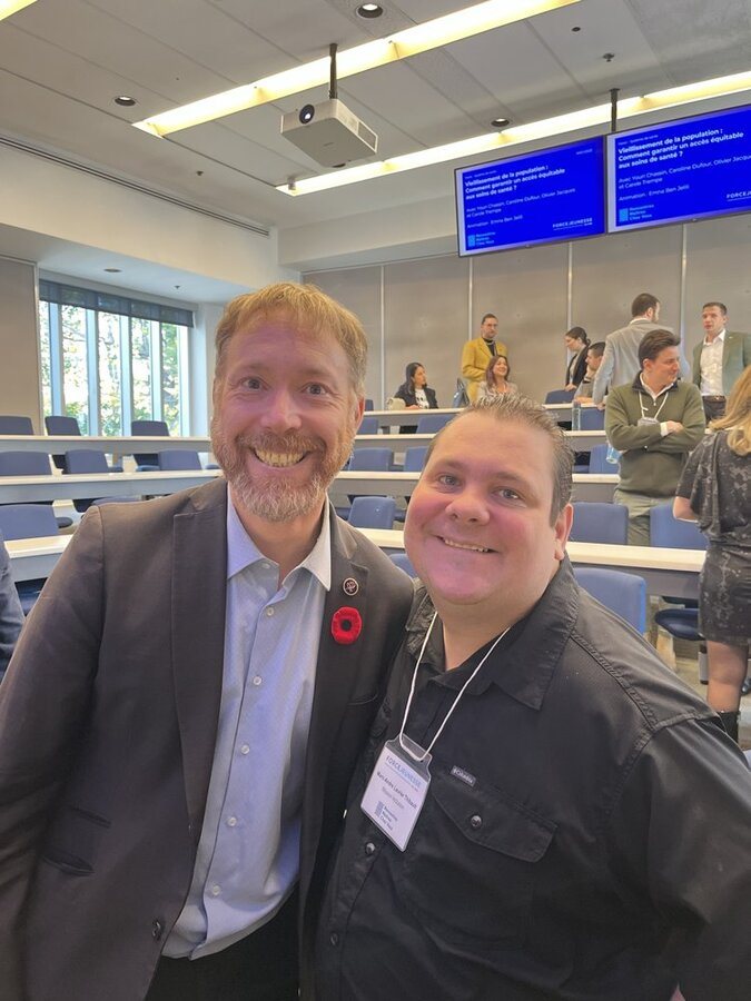 Deux hommes posent dans une salle de conférence.